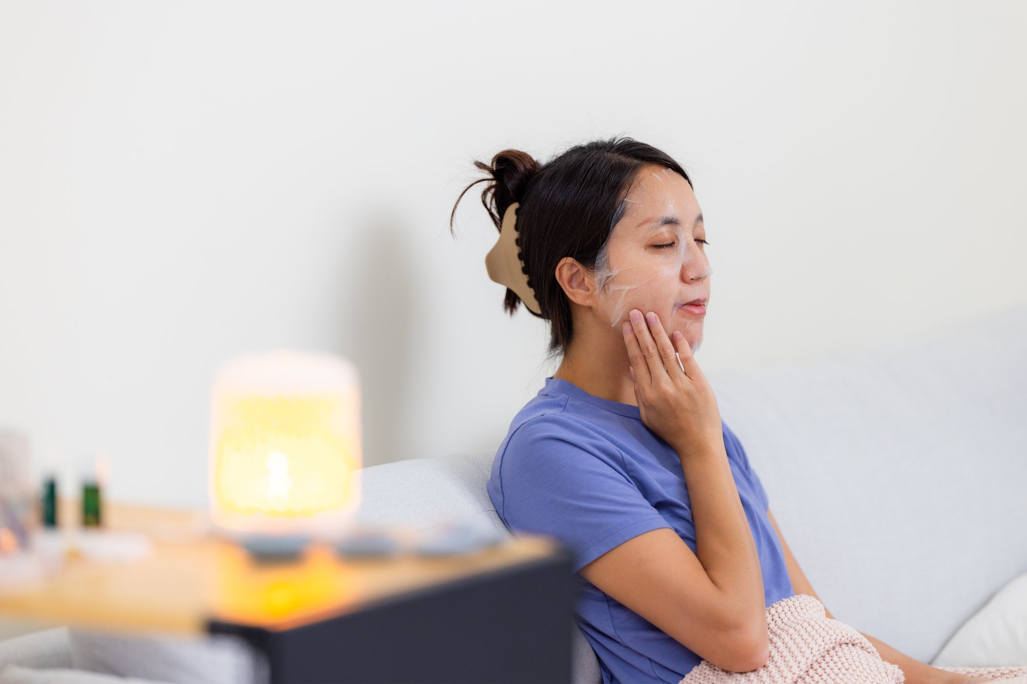 woman-apply-face-mask-at-home-and-sit-on-sofa-2023-11-27-05-29-29-utc