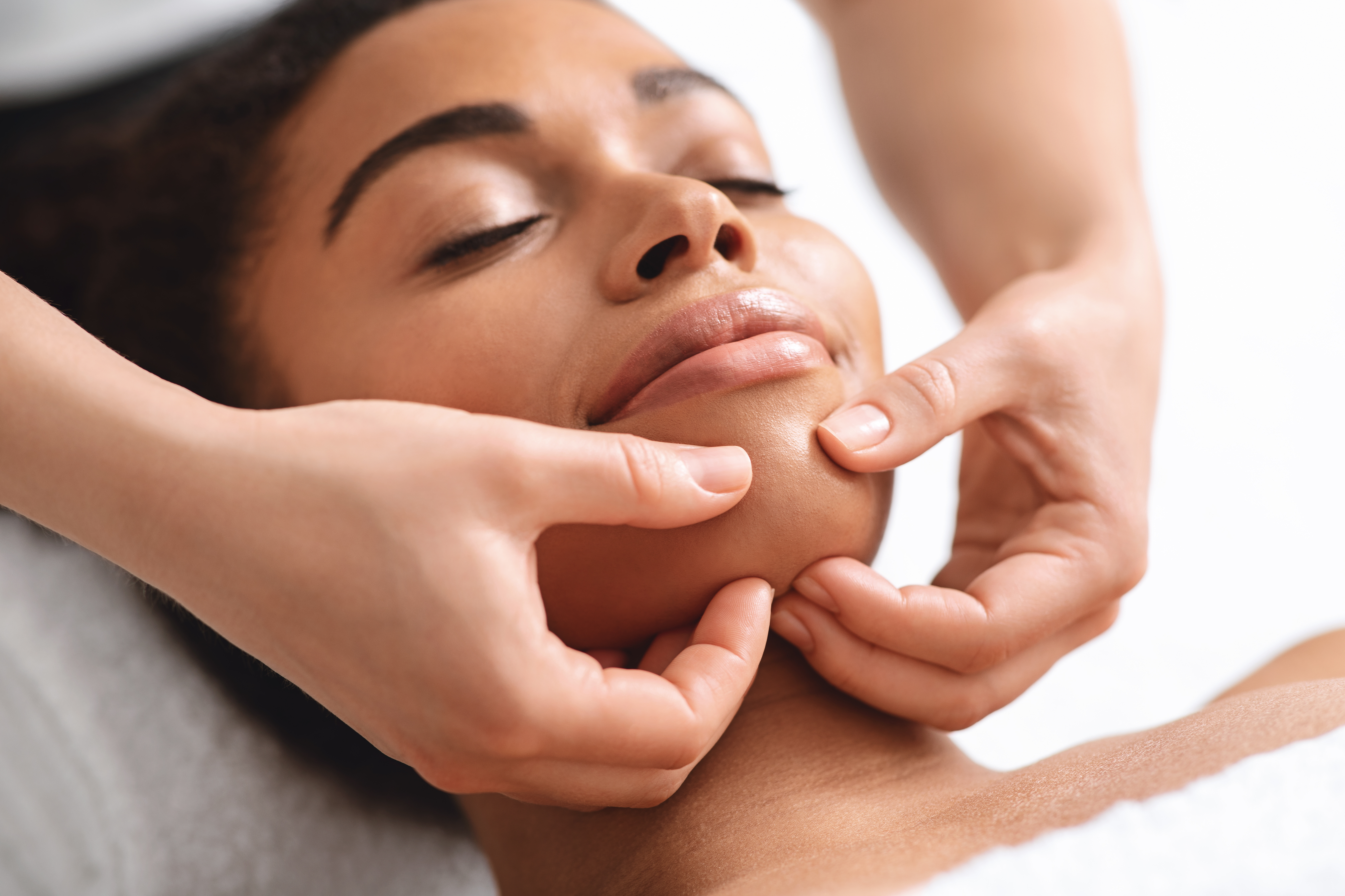 massage-therapist-rubbing-relaxed-black-lady-chin-2023-11-27-05-25-42-utc